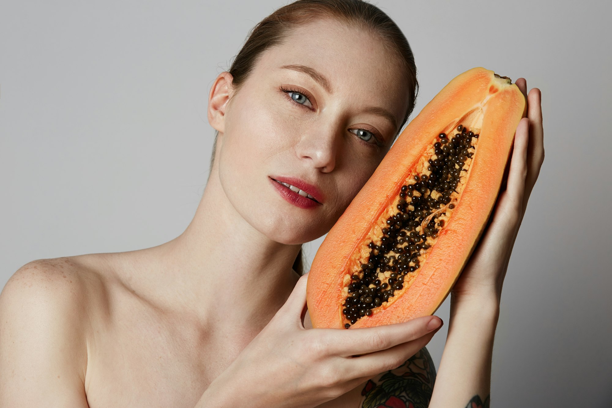 Beauty female model holding juicy papaya slice. Beautiful Joyful teen girl with freckles